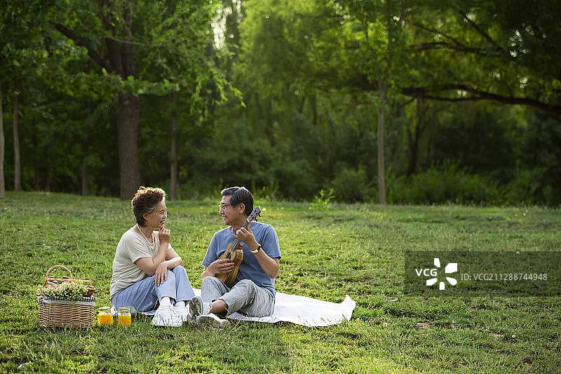 老年伴侣在户外公园野餐弹奏尤克里里琴图片素材