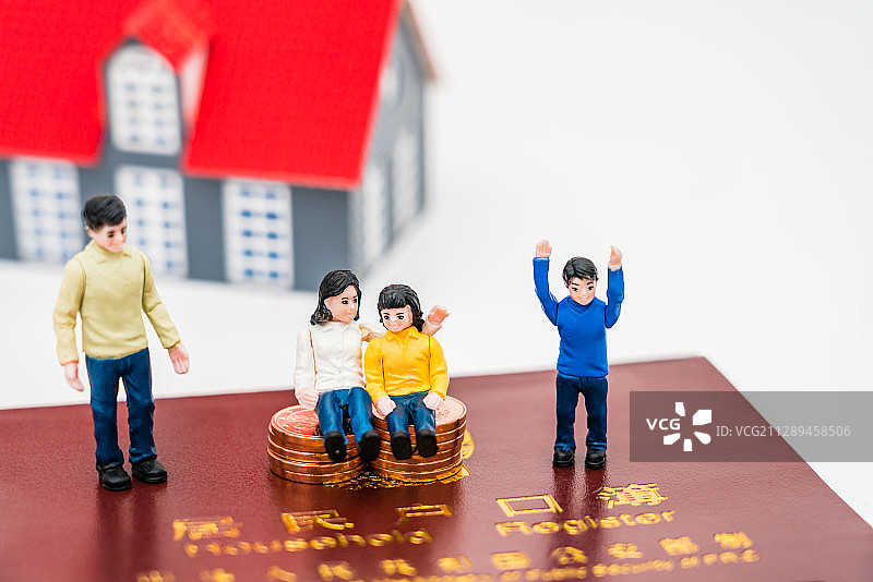 一家四口玩具人偶和房子模型放在户口本上——学区房概念图片图片素材