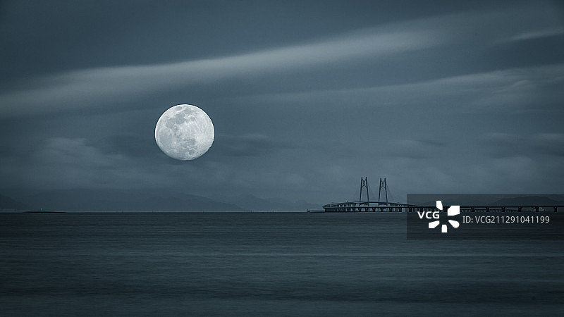利用双重曝光，将港珠澳大桥与一轮明月共同勾勒出海上生明月的画图片素材