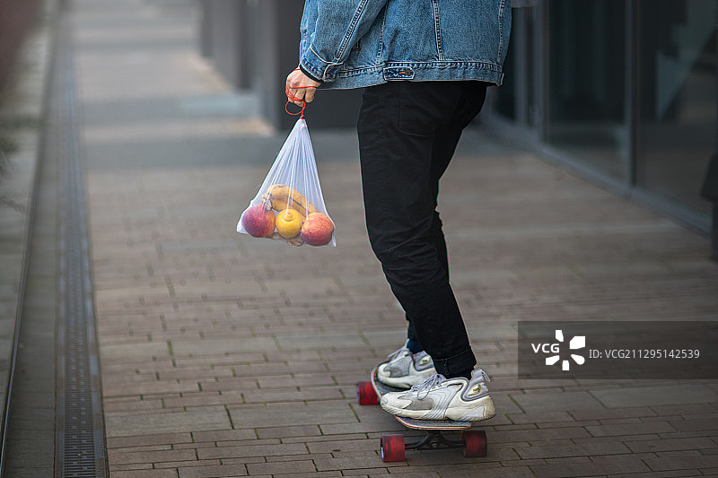 波兰克拉克，一名男子背着可重复使用的水果袋滑滑板图片素材