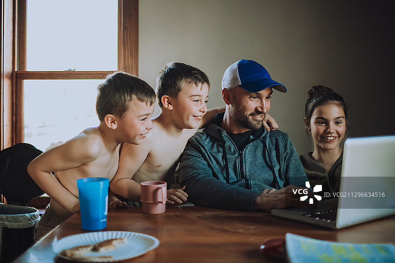 快乐的家庭与双胞胎男孩和女儿与父亲聚在家里笔记本电脑，莉娜，美国图片素材