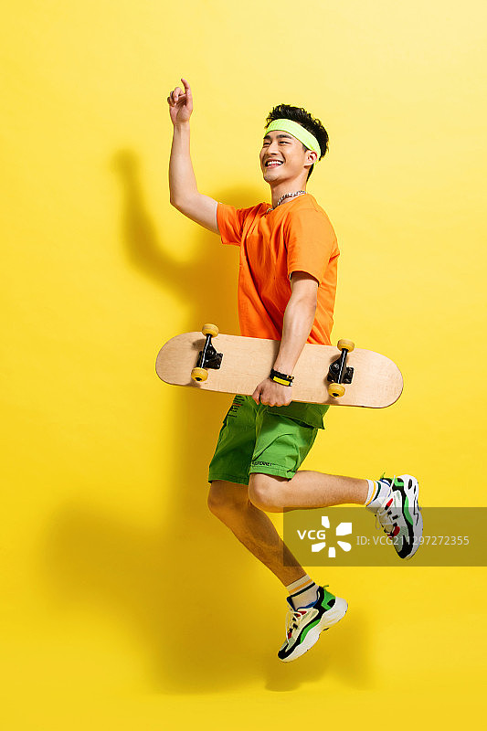 拿着滑板跳跃的活力青年男人图片素材