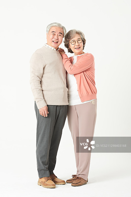 一对老年夫妇微笑着站着女人，把胳膊放在男人的肩上图片素材