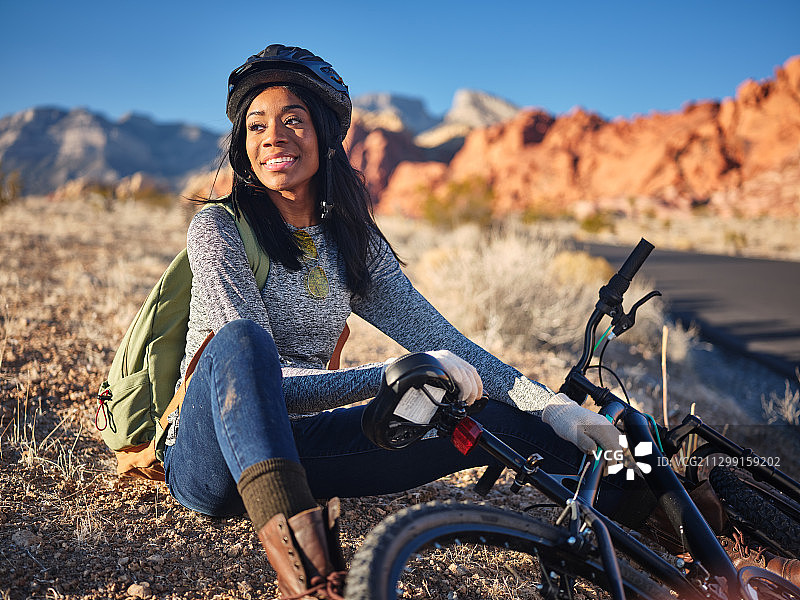 年轻女子骑着自行车坐在沙漠里，美国萨默林南部图片素材