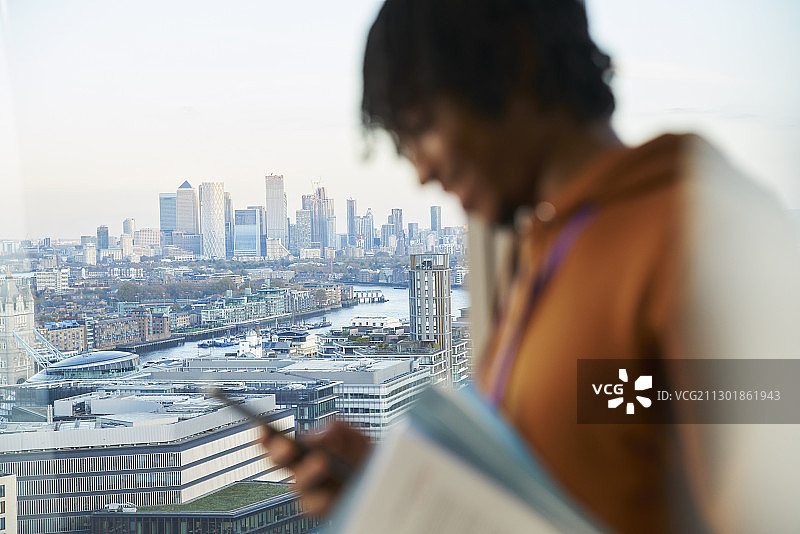 商人在高楼窗口使用智能手机，伦敦，英国图片素材