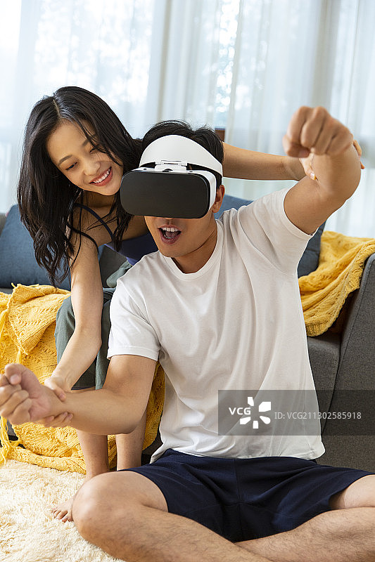 年轻情侣在客厅戴着VR眼镜玩游戏嬉戏图片素材