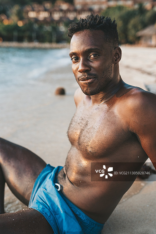 非裔美国人赤膊坐在海滩上，科帕颜，泰国图片素材