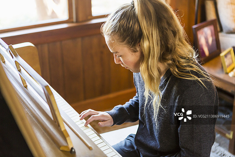 十几岁的女孩在弹钢琴，练习。图片素材