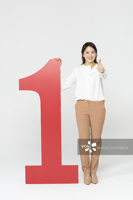 站在1号牌子旁边的女人在白色背景下竖起大拇指图片素材
