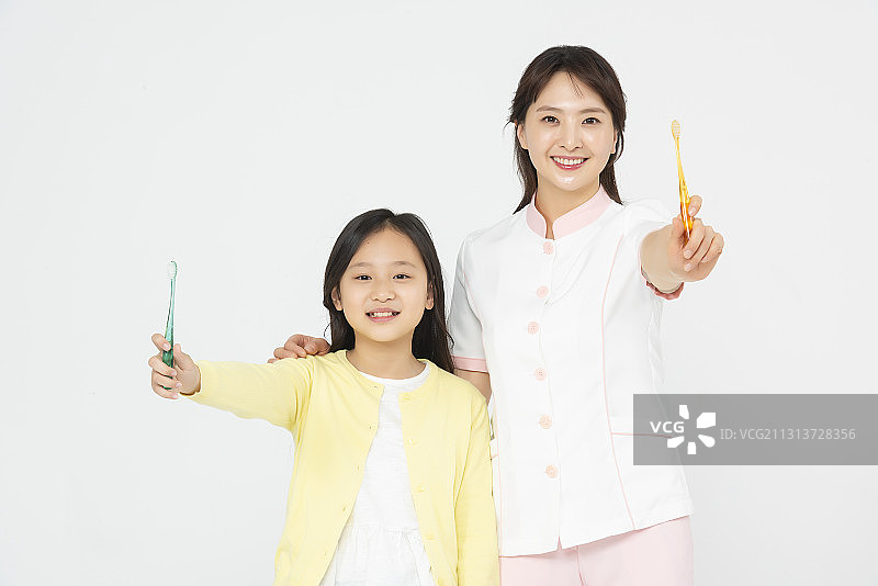 护士和女孩拿着牙刷站在白色的背景上图片素材