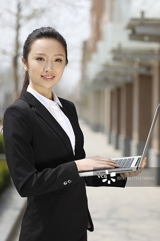 女商人站在户外使用笔记本电脑的肖像图片素材