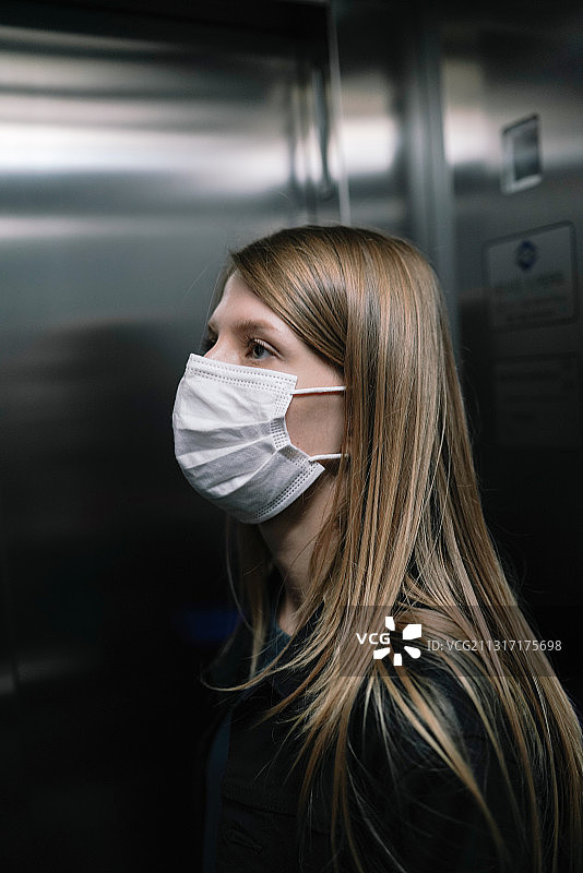 西班牙城市白人女性戴着面罩乘坐电梯图片素材