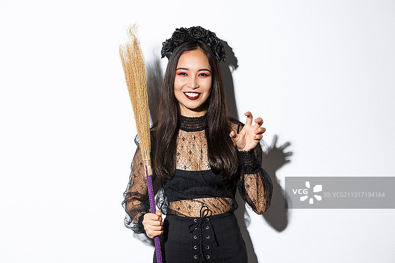 美丽的亚洲女人穿着女巫服装拿着扫帚图片素材