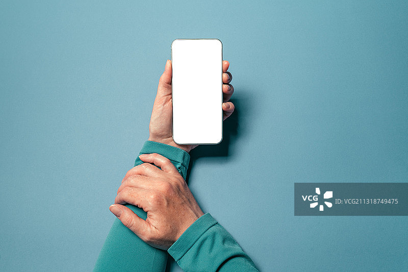 裁剪手握手机与空白屏幕上的蓝色背景图片素材