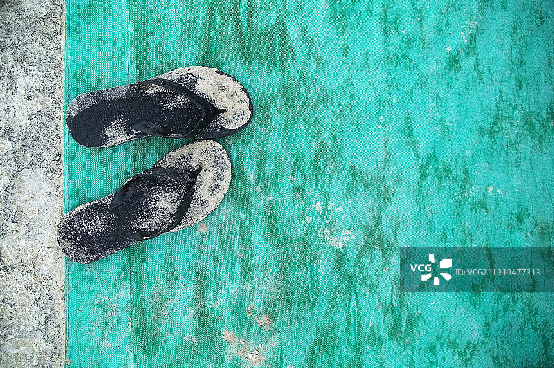 博茨瓦纳，高角度近距离拍摄在绿松石地垫上的沙色黑色人字拖。图片素材