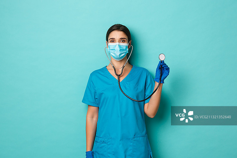 外科医生的肖像戴着外科口罩，而站在蓝色背景图片素材