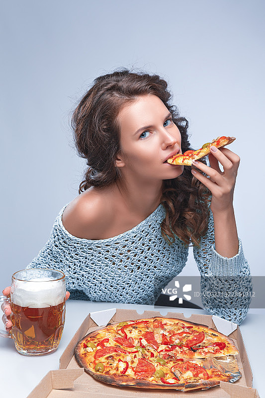 坐在白色背景下吃披萨的女人的肖像图片素材