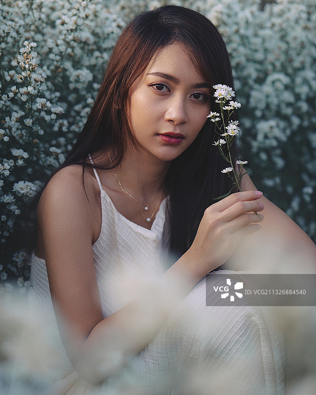 年轻的亚洲女人的肖像拿着花，而站在植物，清迈，泰国图片素材