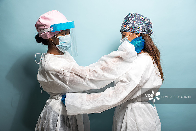 两位女医生互相帮着穿衣服图片素材