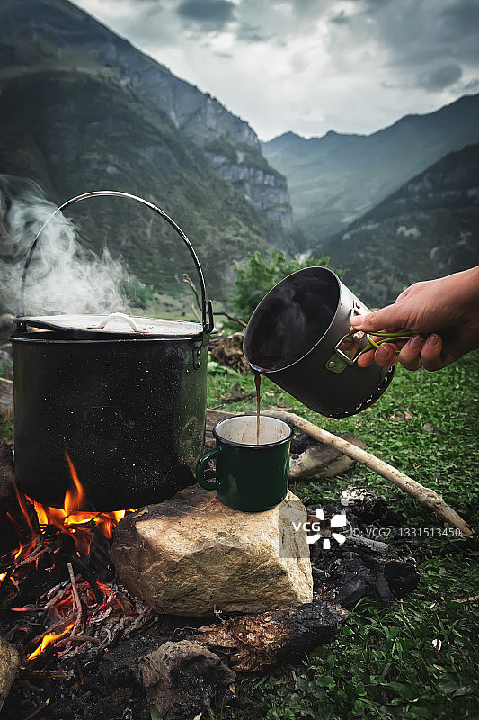 在篝火上倒咖啡对山裁剪的手图片素材