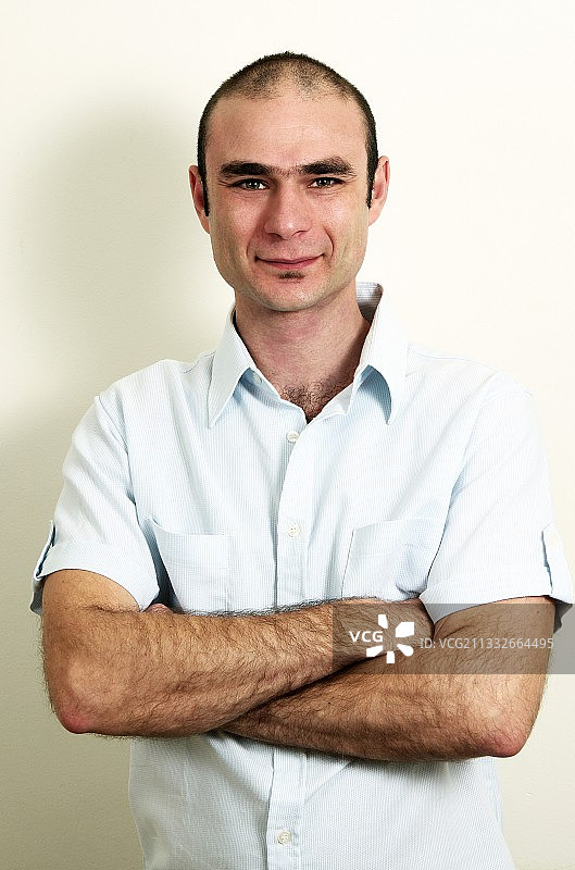 微笑的男人的肖像双臂交叉站在白色的背景图片素材
