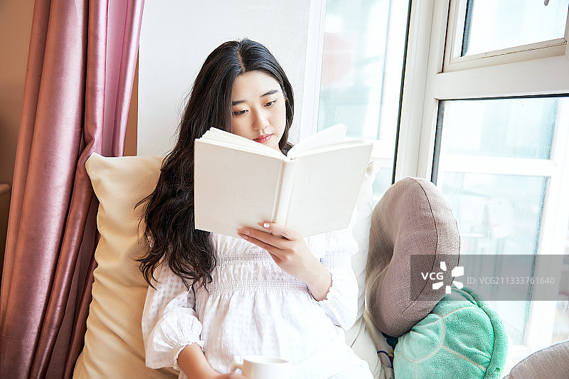 躺在舒适的飘窗上看书的女孩图片素材