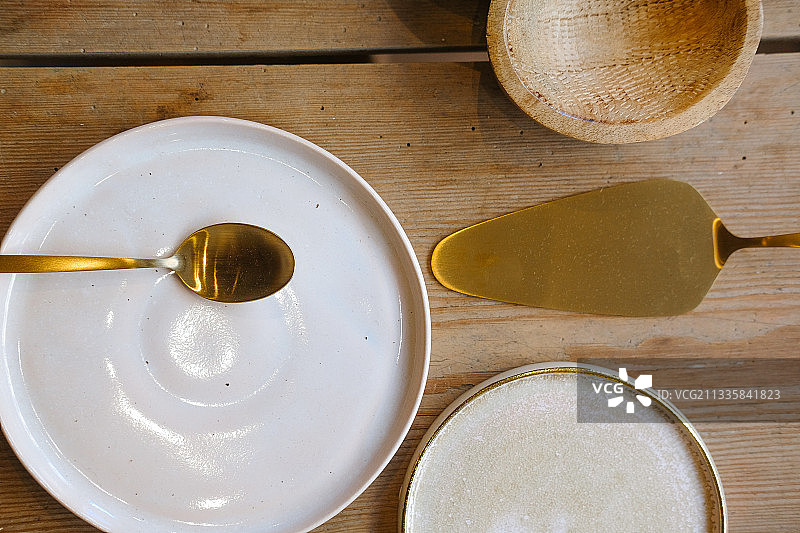木桌上放着金色的厨房和白色的盘子图片素材