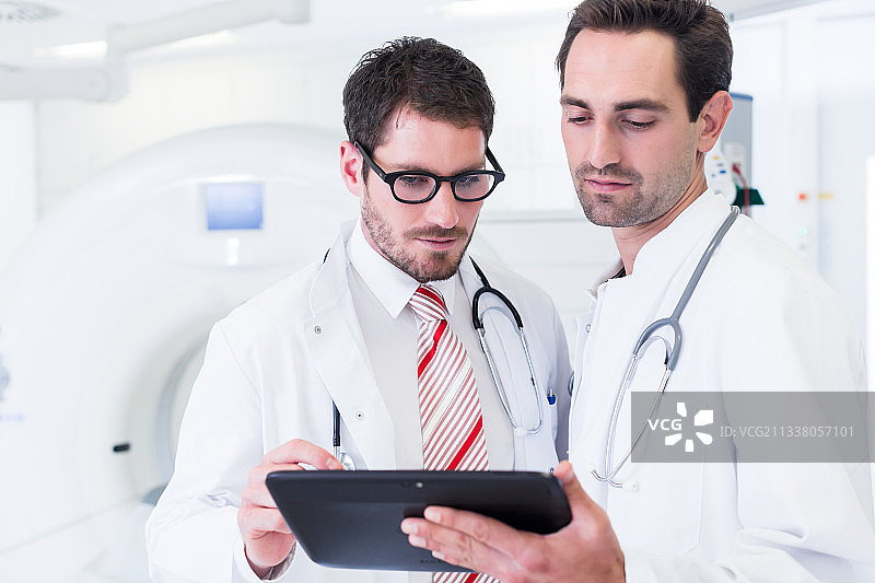 医院里，医生们站在CT机前讨论x光扫描图像图片素材