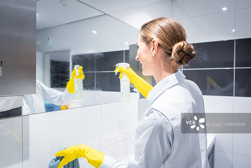 清洁女工或清洁工清洁洗手间的镜子图片素材