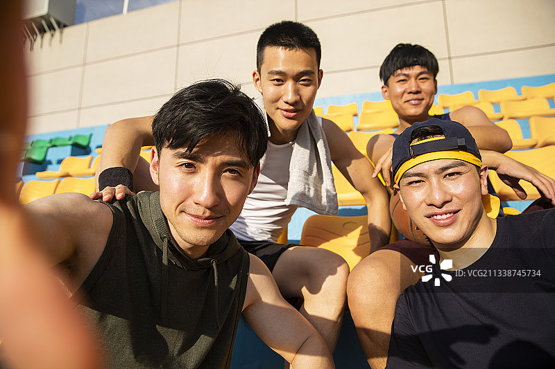 四个青年男子打篮球坐在学校看台休息自拍图片素材