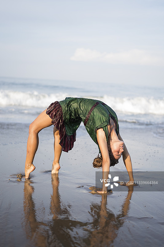 全长度的女人弯在沙滩上对着天空，印度图片素材