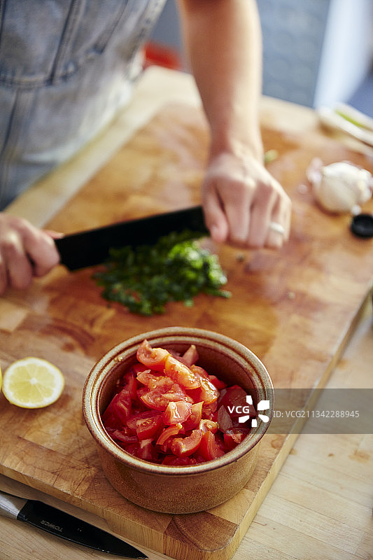 英国，家庭健康烹饪，切碎罗勒做番茄沙拉图片素材