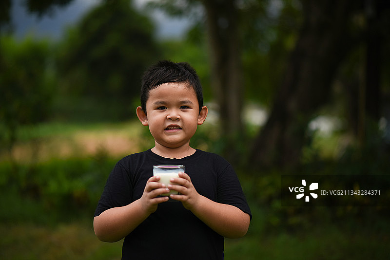 一个小男孩在户外喝着牛奶图片素材
