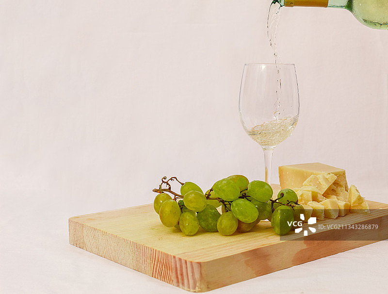 白色背景下，酒倒在切菜板上的特写图片素材