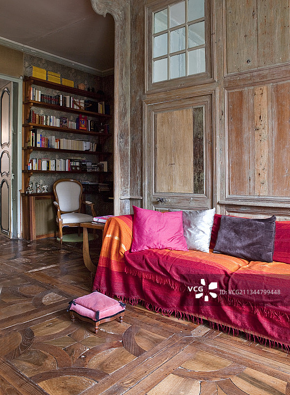 沙发上散落着靠垫，古董拼花地板上点缀着深浅不一的红色图片素材
