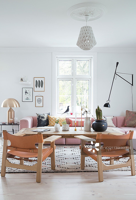 客厅里有粉红色的软垫组合沙发、金色的台灯、质朴的咖啡桌和皮椅图片素材
