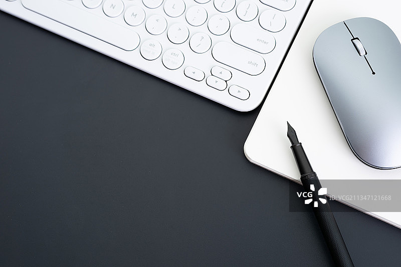 黑背景上的鼠标键盘笔记本和钢笔图片素材