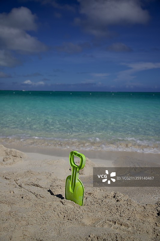 绿色塑料铲在沙滩上的沙子，北大西洋，特克斯和凯科斯群岛图片素材