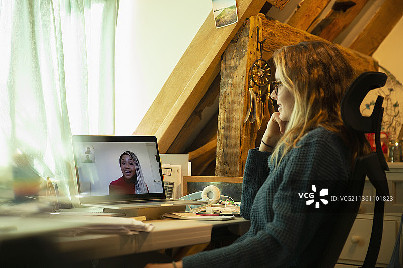 一名女子在家办公，在笔记本电脑屏幕上与同事视频聊天图片素材