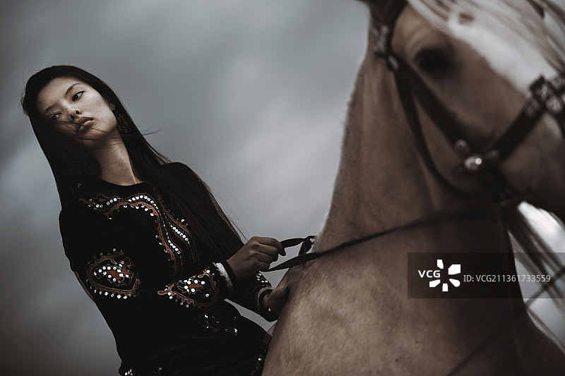 哈萨克妇女穿着民族服装，骑着马图片素材