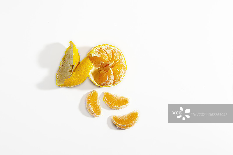 剥了一半的橘子和三个橘角在白色的背景上图片素材