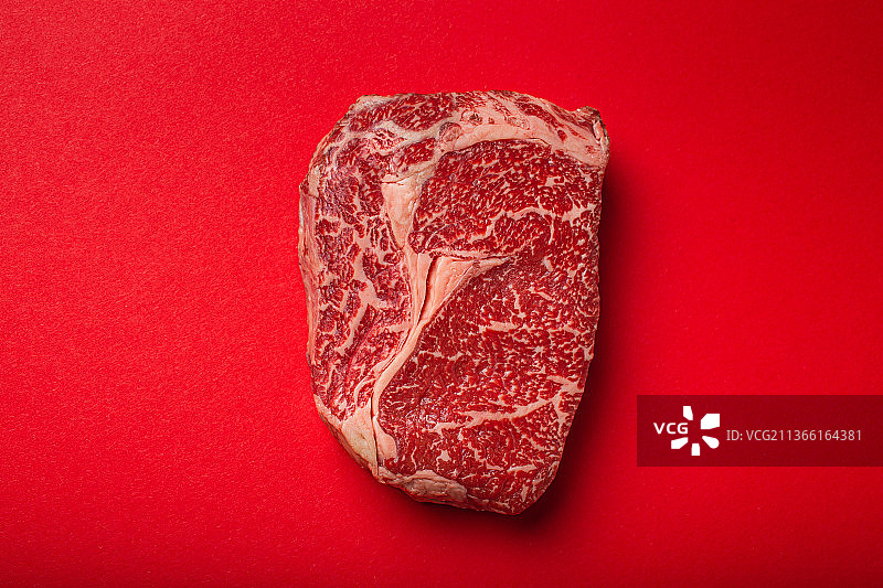 生肉牛肉，上等牛排，肋眼肉在干净的红色背景图片素材