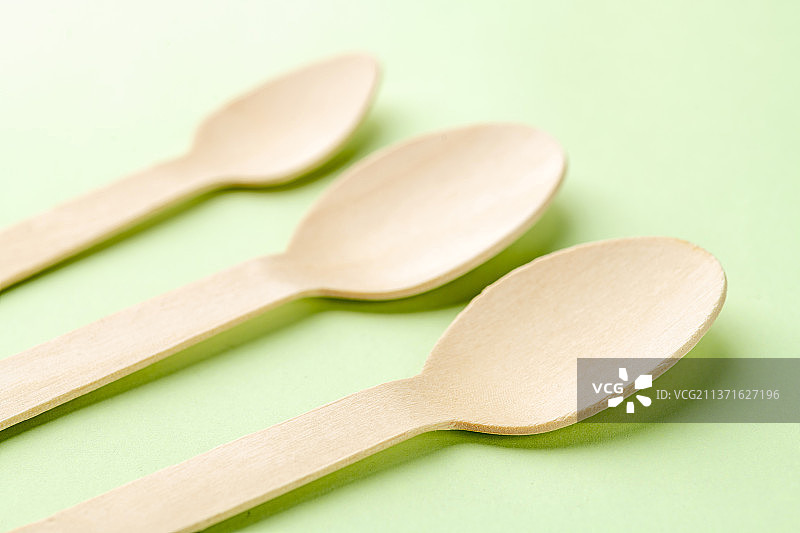 一次性木制餐勺特写绿色莫兰迪色系背景图片素材