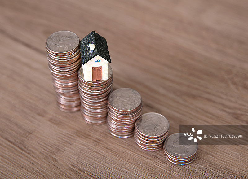 一排递减的美元硬币和一个硬币上的小房子模型图片素材