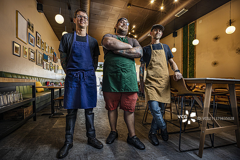 三名自豪的餐厅工作人员在他们的餐厅里摆姿势拍照图片素材