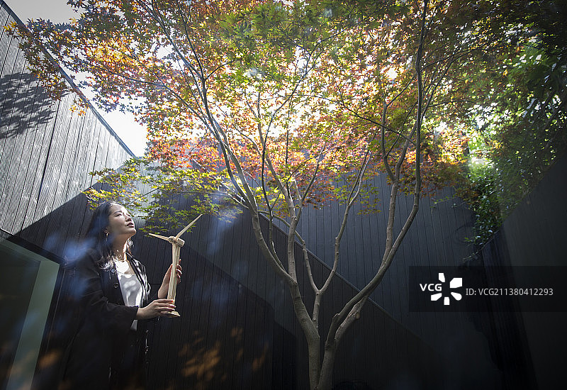 女工程师与风轮机模型在庭院与树图片素材