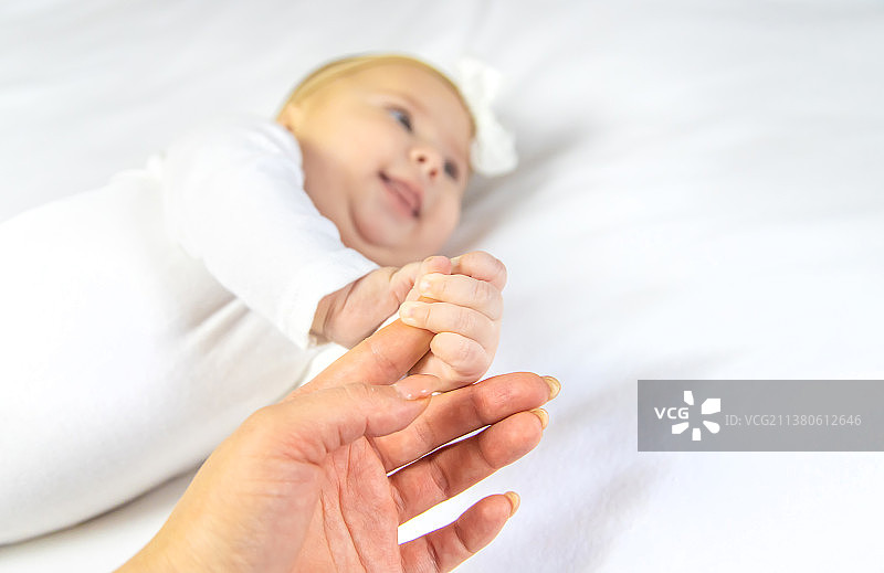 婴儿的手与母亲的手在白色背景下选择性聚焦图片素材