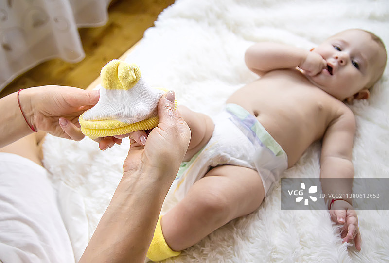 妈妈把袜子放在宝宝身上选择性聚焦图片素材