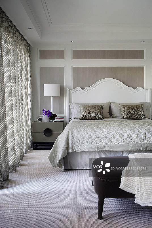 在优雅的卧室里，双人床上有白色的弧形木制床头板，靠在带白色框架的木墙板上图片素材