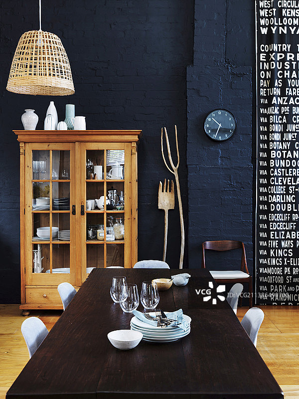 在深蓝色墙壁的开放式客厅里，有一张带椅子和展示柜的餐桌图片素材